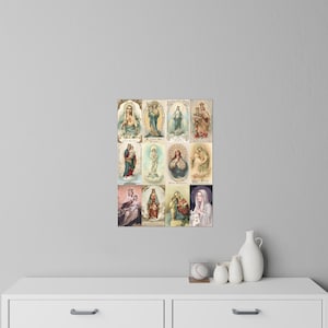 May include: A framed print featuring twelve vintage religious illustrations of the Virgin Mary. The images showcase various depictions of Mary, with soft colours and ornate details. The artwork is displayed on a white surface.