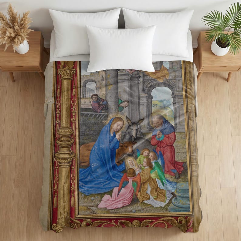 Plush blanket featuring a Nativity scene with Mary in blue robes, Joseph in red, baby Jesus, angels, and animals in an architectural setting with ornate gold and red decorative borders, displayed on a bed with white pillows