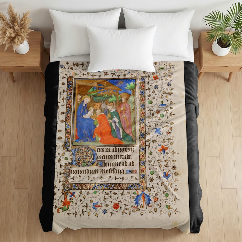 Plush blanket featuring a medieval illuminated manuscript page depicting the Nativity scene with ornate decorative borders and floral patterns, displayed on a bed with white pillows