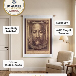 Holy Face plush blanket hung flat on a warm plaster wall from a wooden rod beside an upholstered reading armchair and a lamp