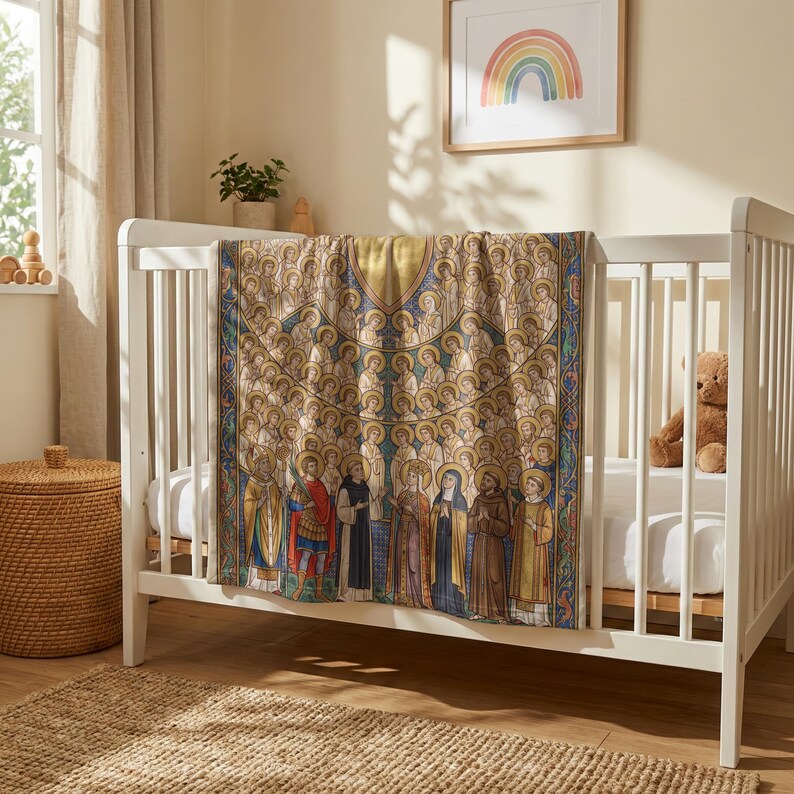 All Saints plush blanket hung over the rail of a white crib with a teddy bear inside
