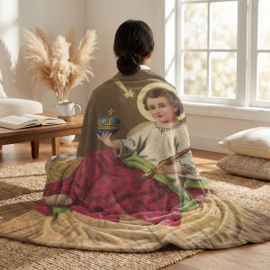 Christmas plush blanket wrapped around a woman's shoulders as she sits on the floor