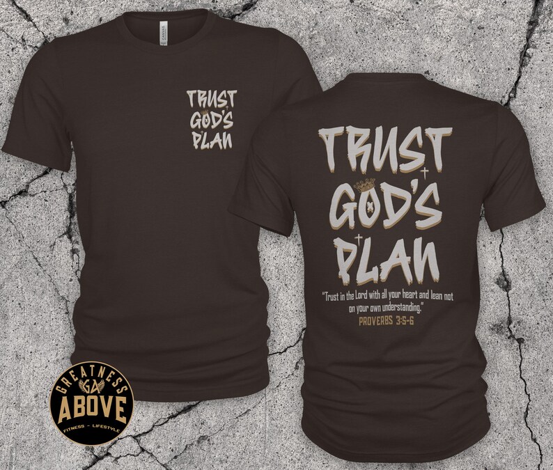 May include: A dark brown short-sleeve t-shirt featuring the text TRUST GOD'S PLAN on the front left chest and a larger version on the back with a crown, two small crosses, and the scripture text Trust in the Lord with all your heart and lean not on your own understanding. PROVERBS 3:5-6.