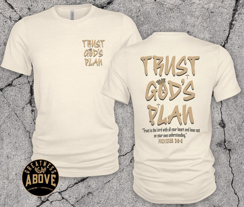 May include: A cream-colored short-sleeve t-shirt featuring the text TRUST GOD'S PLAN on the front left chest. The back displays the same text in larger font with a crown icon, plus the verse Trust in the Lord with all your heart and lean not on your own understanding. PROVERBS 3:5-6.