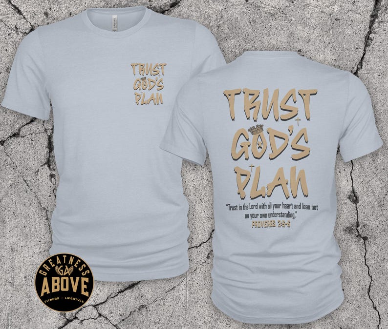 May include: A light blue t-shirt featuring the text TRUST GOD'S PLAN in tan on the front left chest. The back displays the same text in a larger font with a crown icon, plus the verse Trust in the Lord with all your heart and lean not on your own understanding. PROVERBS 3:5-6.