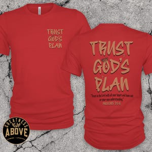 May include: A red short-sleeved t-shirt featuring the text TRUST GOD'S PLAN in tan on the front left chest. The back displays the same text in a larger font, along with the scripture Trust in the Lord with all your heart and lean not on your own understanding. PROVERBS 3:5-6.