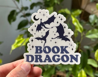 May include: A white sticker with a blue silhouette of a dragon curled around a book. The sticker says "BOOK DRAGON" in blue letters.