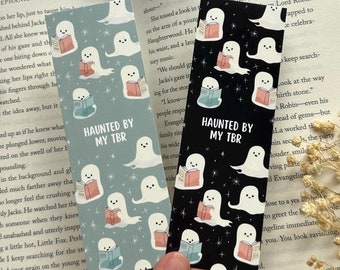 May include: Two black and blue bookmarks with a ghost reading a book pattern. The text on the bookmarks reads "Haunted by my TBR".
