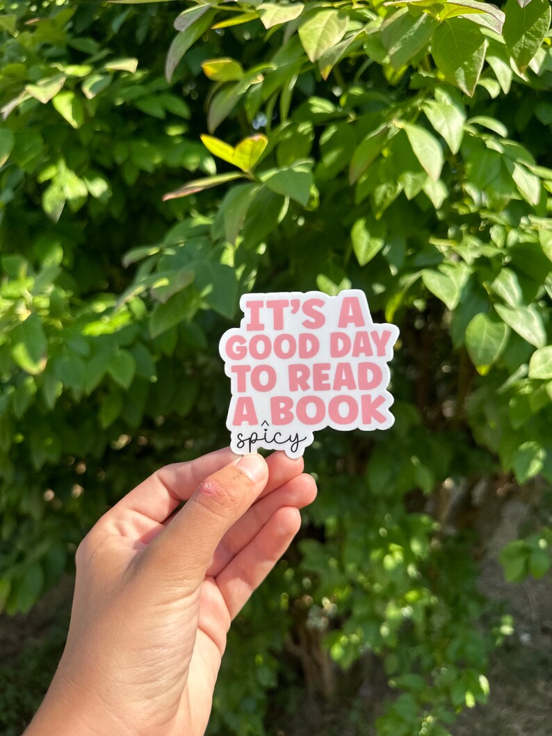 May include: Pink sticker with the text "It's a good day to read a book" and the word "spicy" written below in cursive.