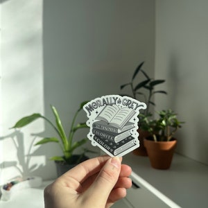 May include: A sticker with a stack of books and the text "Morally Grey is my favorite color".
