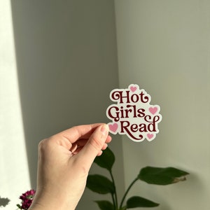 May include: A white sticker with the text "Hot Girls Read" in maroon lettering and pink hearts.