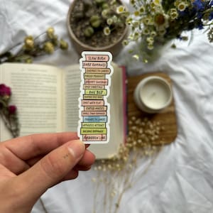 Może przedstawiać: Naklejka z  stosu książek, każda książka ma inny kolor i inny romantyczny trop napisany na niej. Tropami są: Slow Burn, Dark Romance, Enemies to Lovers, Forced Proximity, Grumpy Sunshine, Spicy Fairytale, One Bed, Fated Mates, Friends to Lovers, Opposites Attract, Holiday Romance i Forbidden Love.