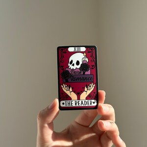 May include: A tarot card with a red background and black and white skull illustration. The card is labeled "XIII Dark Romance The Reader".