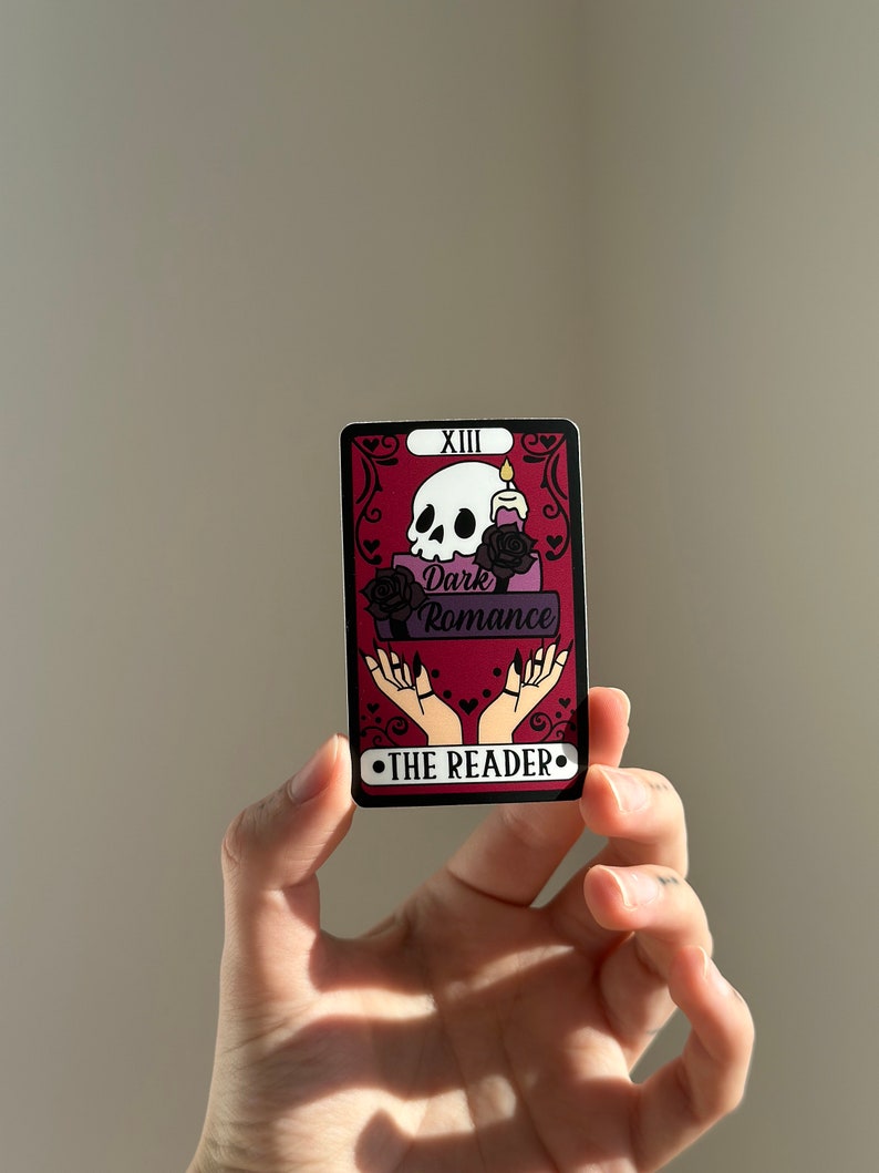 May include: A tarot card with a red background and black and white skull illustration. The card is labeled "XIII Dark Romance The Reader".