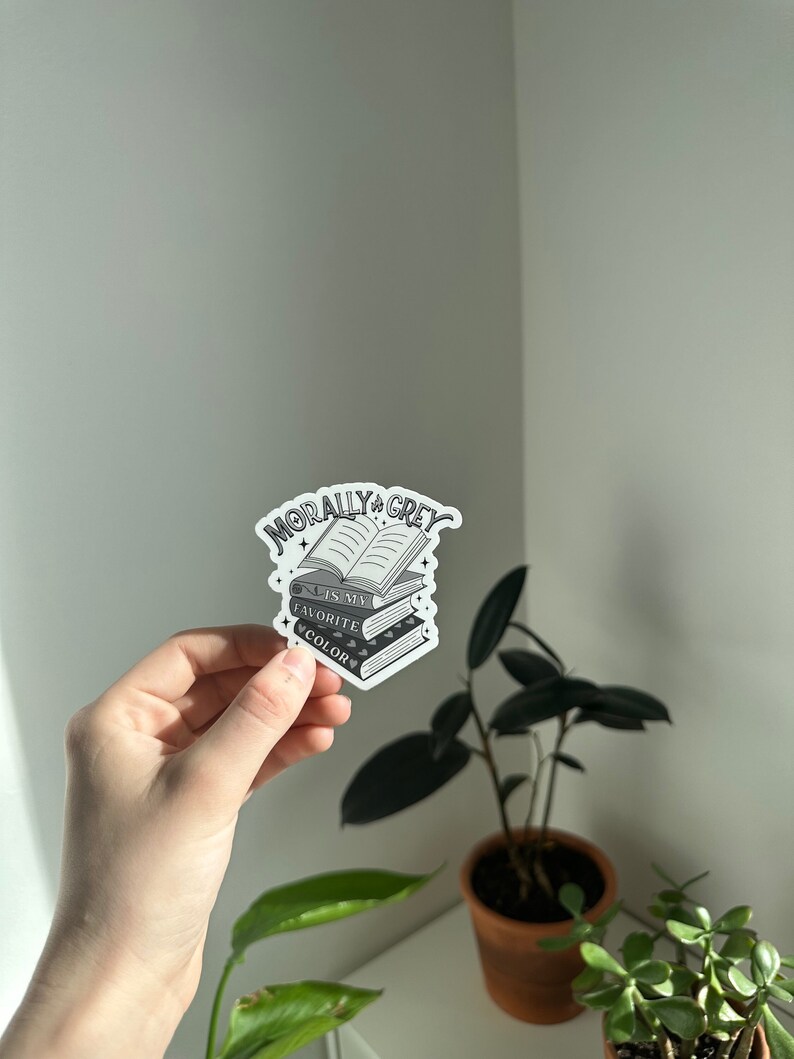 May include: A white sticker with a stack of books and the text "Morally Grey is my favorite color".
