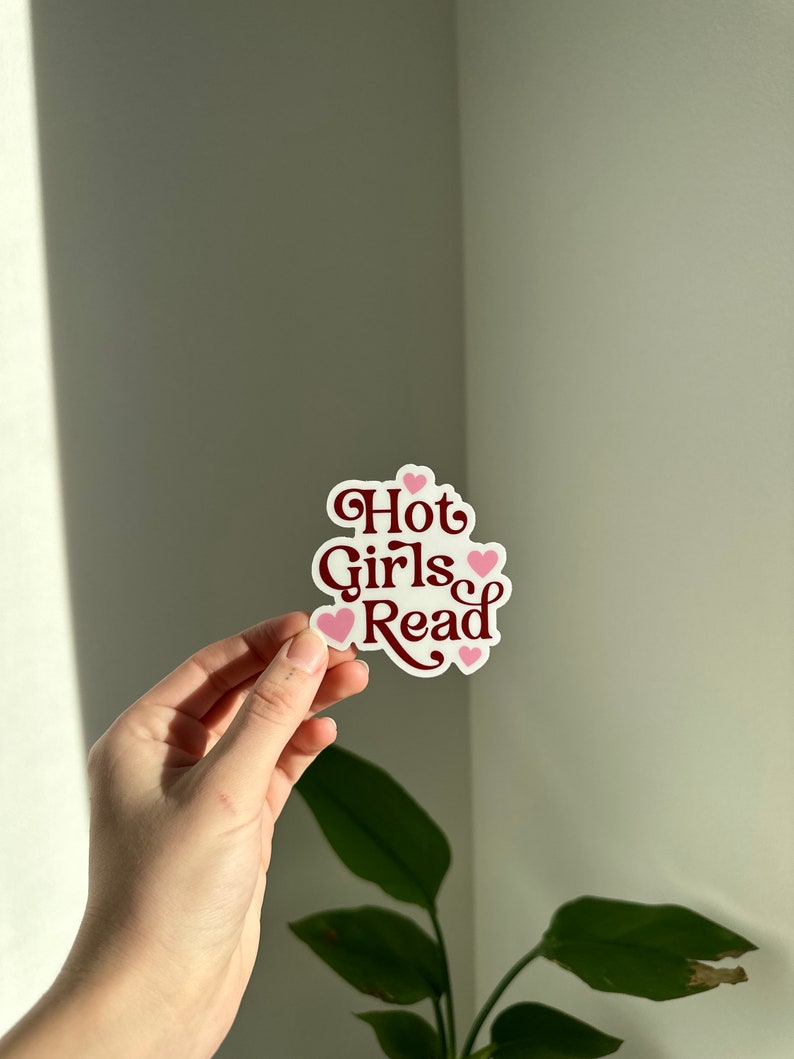 May include: A white sticker with the text "Hot Girls Read" in maroon lettering and pink hearts.