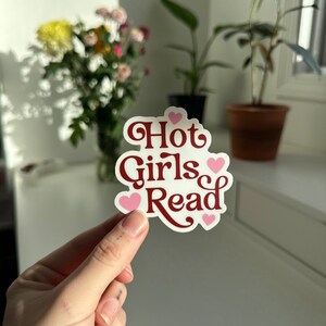 May include: A white sticker with the text "Hot Girls Read" in maroon lettering and pink hearts.