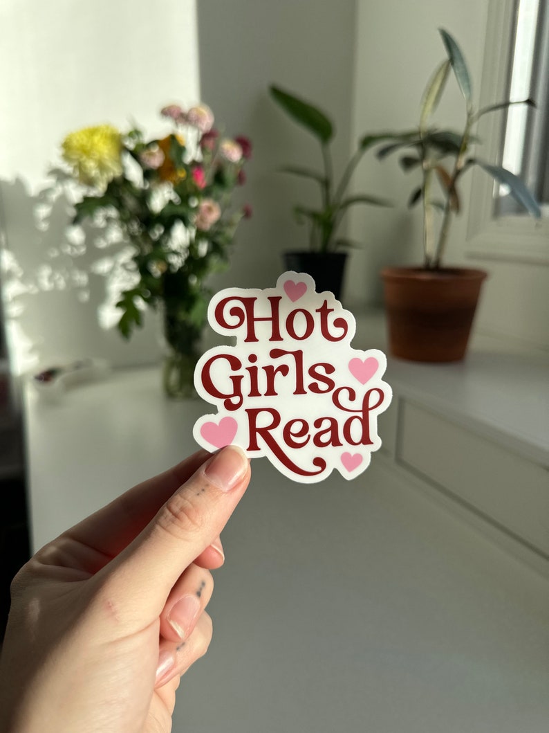 May include: A white sticker with the text "Hot Girls Read" in maroon lettering and pink hearts.
