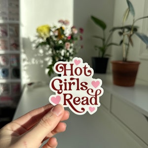 May include: A white sticker with the text "Hot Girls Read" in maroon lettering and pink hearts.