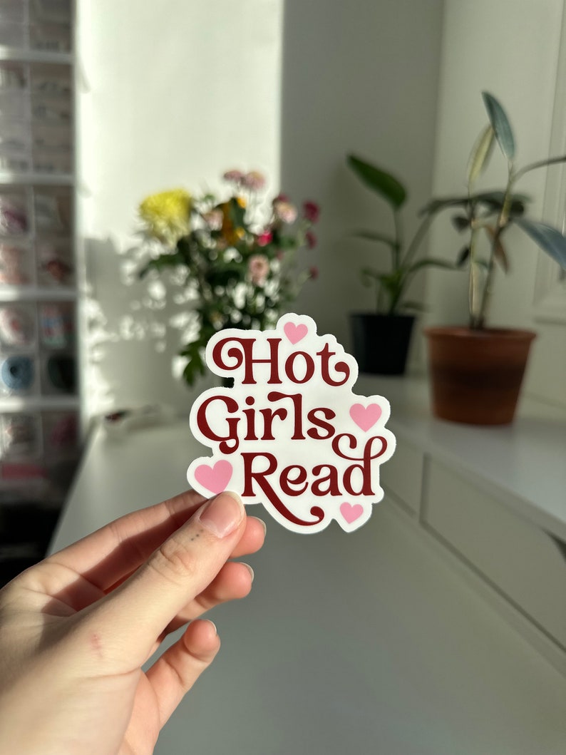 May include: A white sticker with the text "Hot Girls Read" in maroon lettering and pink hearts.
