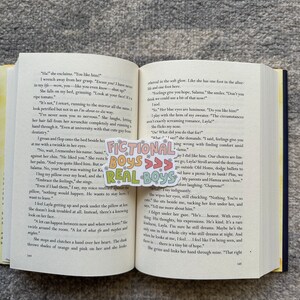 K&ouml;nnte beinhalten: Eine Nahaufnahme eines Buches, das auf einer Seite mit Text &uuml;ber die Gef&uuml;hle einer jungen Frau ge&ouml;ffnet ist. Der Text lautet "Feelings give you hope, Salama." Das Buch liegt auf einem Bett mit einer bunten Tagesdecke.