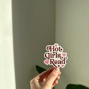 May include: A white sticker with the text "Hot Girls Read" in maroon lettering and pink hearts.