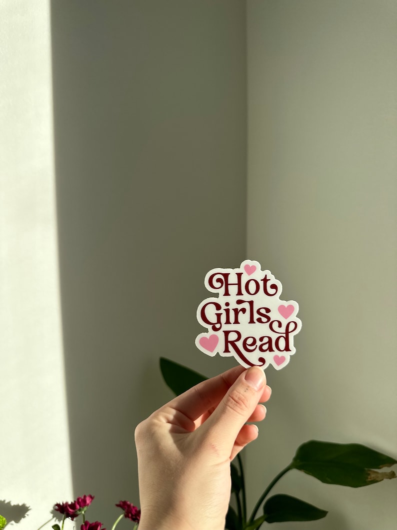 May include: A white sticker with the text "Hot Girls Read" in maroon lettering and pink hearts.