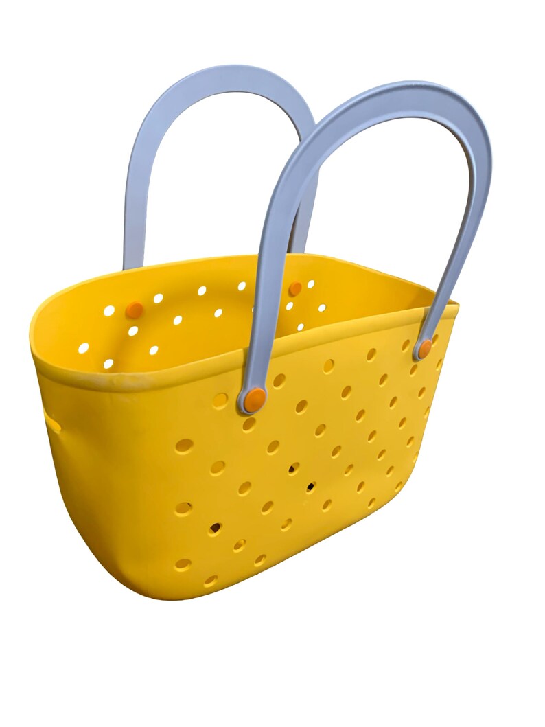 May include: A yellow tote bag with a perforated design. The bag has two gray handles and orange accents. The bag is made of a durable material and is designed for carrying items. The bag is a bright and cheerful color.