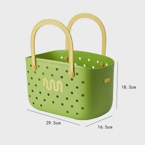 May include: A green plastic basket with yellow handles. The basket has a perforated design with a wavy graphic and is 29.5 cm long, 16.5 cm wide, and 18.3 cm high. The handles are arched and attached to the sides.