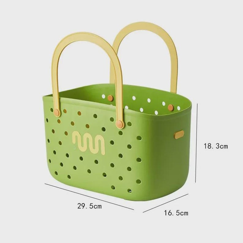May include: A green plastic basket with yellow handles. The basket has a perforated design with a wavy graphic and is 29.5 cm long, 16.5 cm wide, and 18.3 cm high. The handles are arched and attached to the sides.