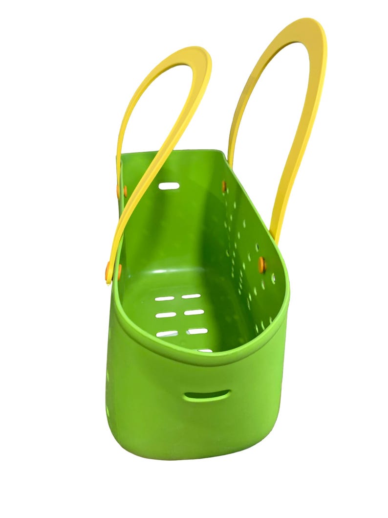 May include: A bright green plastic basket with yellow handles. The basket has a rectangular shape with a series of holes and slots for drainage. The handles are arched and attached to the top of the basket.