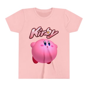 May include: Pink t-shirt featuring a pink Kirby character and the word "Kirby" in a pink, white and yellow font.