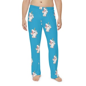 May include: Light blue pajama trousers with a repeating pattern of a cartoon unicorn wearing a party hat. The unicorn has a white body, blue mane, and a gold horn. The trousers have a relaxed fit.