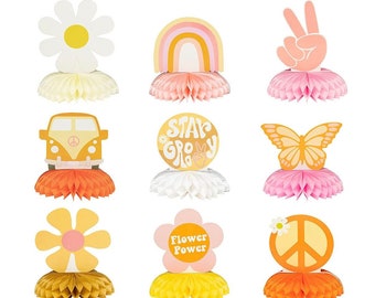 May include: Nine colorful paper centerpieces with a 70s theme. The centerpieces feature a daisy, rainbow, peace sign, butterfly, van, flower power, and a groovy text design.