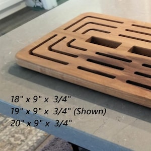 May include: A rectangular wooden cutting board with a series of cut-out slots and geometric patterns. The board is approximately 19 inches long, 9 inches wide, and 0.75 inches thick. The text "3 Sizes Available" is visible.