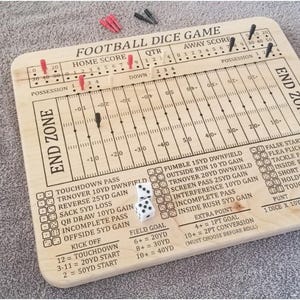 Puede incluir: Tablero de juego de dados de fútbol de madera con líneas de campo grabadas, zonas de anotación y secciones de puntuación. Incluye dados, clavijas e instrucciones del juego. El tablero mide aproximadamente 30 cm por 25 cm.