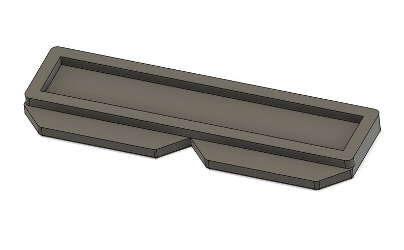 May include: A gray plastic mold for making a rectangular shape with a raised edge.