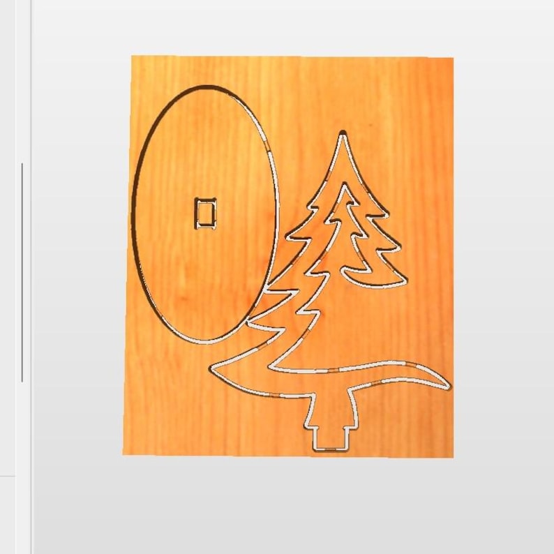 May include: A light brown wooden board featuring two laser-cut shapes: a large vertical oval with a small square cutout in the center, and a stylized evergreen tree silhouette positioned to the right of the oval shape on the wood surface.