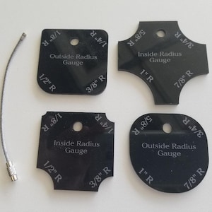 May include: Four black plastic radius gauges with different sized curves. The gauges are labelled with the radius size in inches, such as 1/8", 1/4", 3/8", 1/2", 5/8", 3/4", 7/8", and 1". The gauges are labelled "Outside Radius Gauge" and "Inside Radius Gauge".
