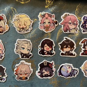 May include: A collection of fifteen colorful anime-style character stickers. Each sticker features a unique character design with detailed facial expressions and outfits. The stickers are on a teal background.