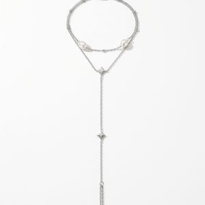 May include: A silver-toned multi-strand bracelet featuring two white pearls and two small star-shaped charms. The jewellery piece includes a delicate chain design with a lobster claw clasp, an adjustable extender chain, and a small rectangular metal tag.