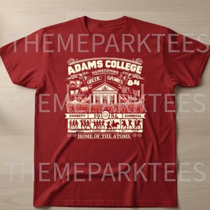 May include: A red t-shirt with a white graphic design. The design features the text "ADAMS COLLEGE HOMECOMING GREEK GAMES 84" with additional text and illustrations. The shirt also includes the text "HOME OF THE ATOMS".