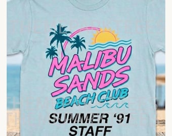May include: Light blue t-shirt with a graphic design featuring the words "Malibu Sands Beach Club" in pink and blue, with palm trees, a sun, and waves. The text "Summer '91 STAFF" is below the main text.