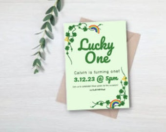 May include: Green invitation with a shamrock border and a rainbow. The text reads "Lucky One" and "Calvin is turning one! 3.12.23 @ 5pm".