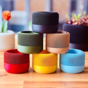May include: A set of six colourful, geometrically patterned, cylindrical containers. The containers are made of a textured plastic material and are arranged in a pyramid shape.