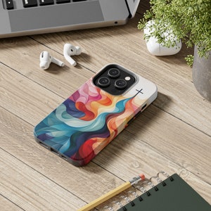 May include: A colorful phone case with an abstract design featuring swirling lines and a cross. The case is designed for an iPhone with a camera bump.