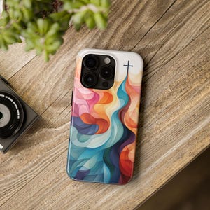 May include: A colorful phone case with a cross design. The case features a blue, green, orange, and red abstract pattern. The cross is black and is located at the top of the case.