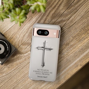 May include: A white phone case with a silver cross and the text "NO WEAPON FORMED AGAINST ME SHALL PROSPER Isaiah 54:17".