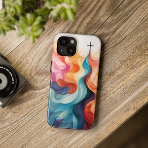 May include: A colorful phone case with an abstract design featuring a cross at the top. The case is made of a hard plastic material and has a glossy finish.