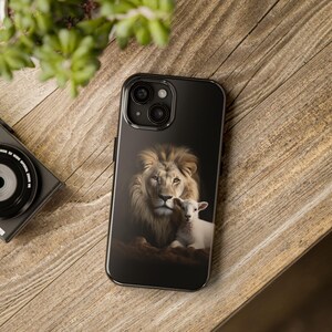 May include: A black phone case with a lion and a lamb on it. The lion is brown and has a white mane. The lamb is white and has a black nose. The background is black.